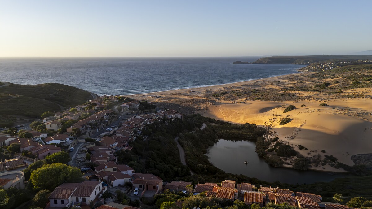 Aerial view of Torre dei Corsari at sunset: the village, the lagoon, the dunes and the Costa Verde sea