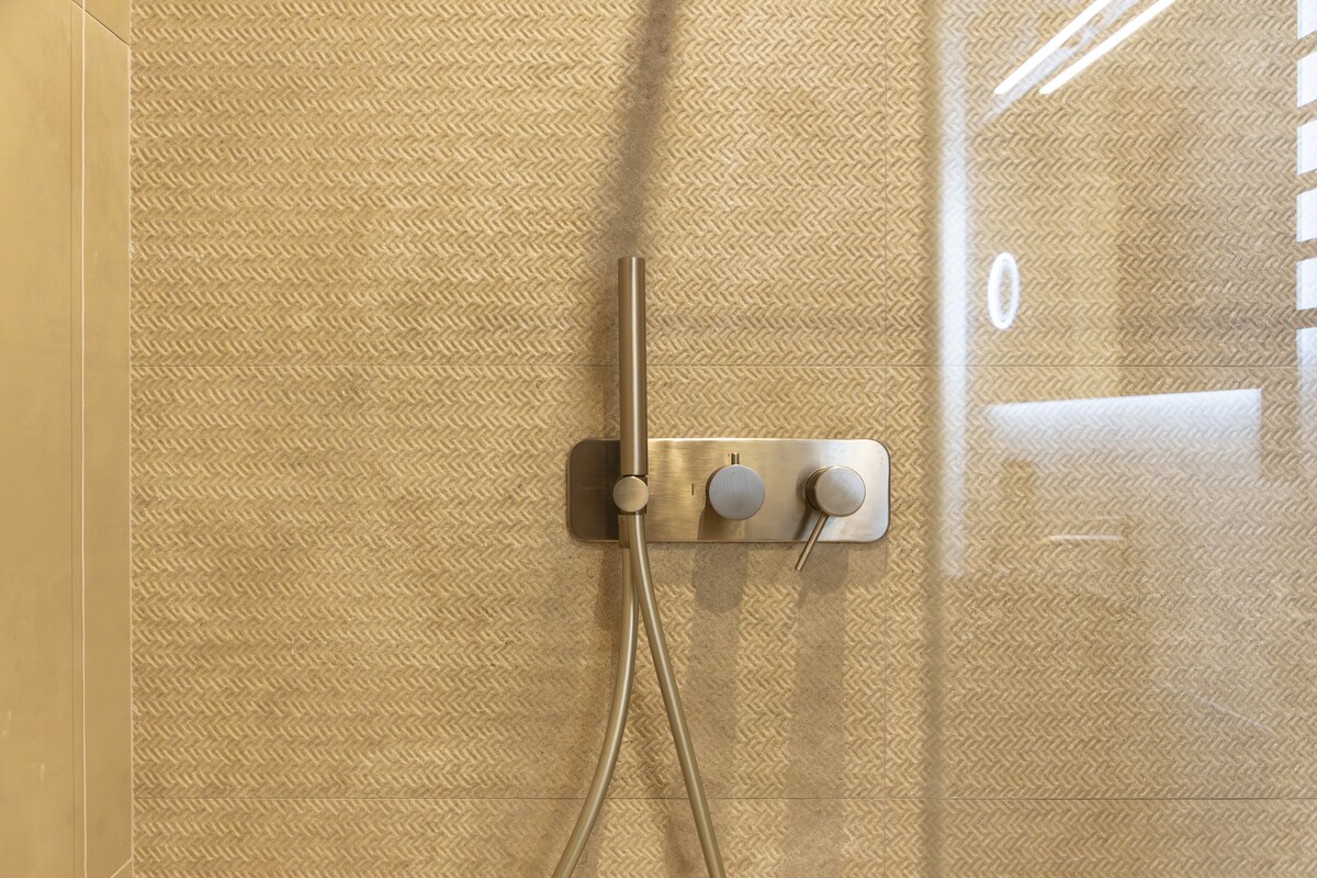 A design shower with brushed fittings and herringbone tiles
