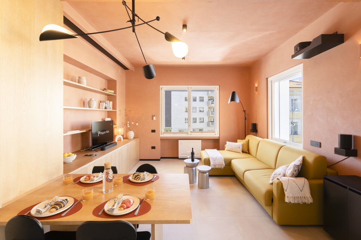Living room with a yellow corner sofa and terracotta walls in a Propertize apartment in Cagliari