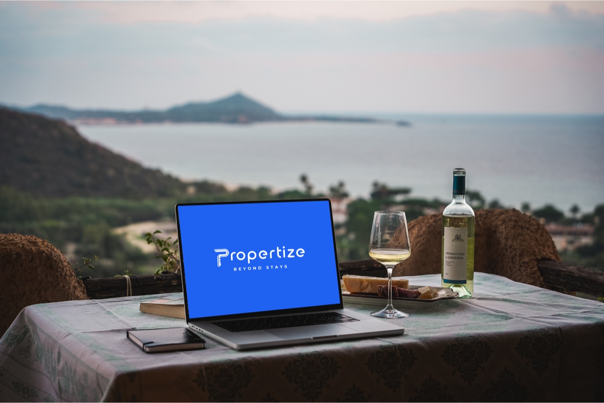 A workstation with a laptop and a notepad on an outdoor table with a sea view in Sardinia